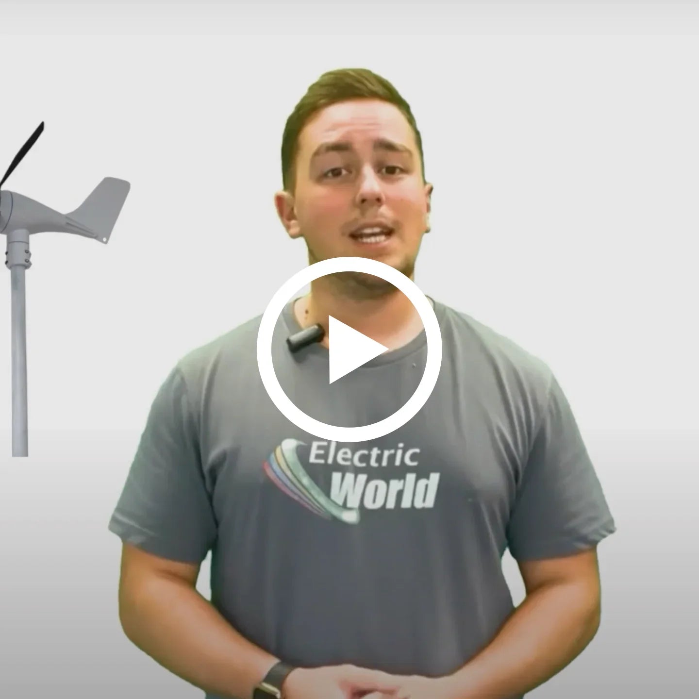 Man presenting beside a small wind turbine, wearing Electric World t-shirt, video overlay.