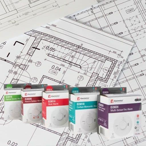 Home safety alarms and detectors displayed in front of architectural blueprints