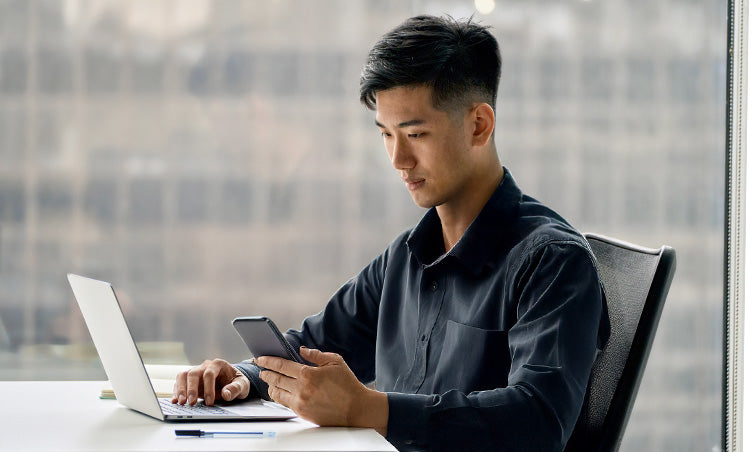Man using a laptop and smartphone in an office setting